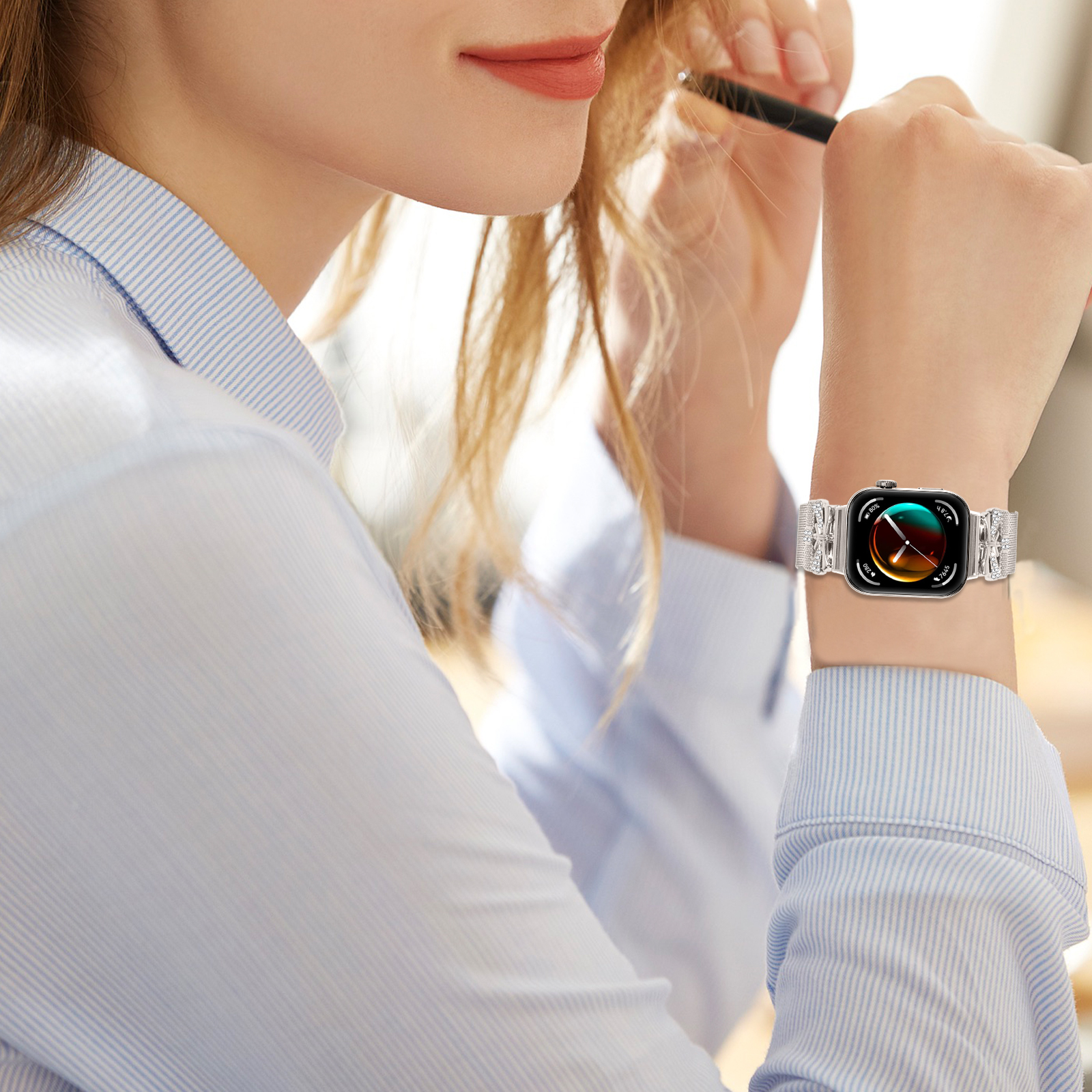 Eine Frau mit hellblauem Hemd und Smartwatch. Sie hält einen Stift.