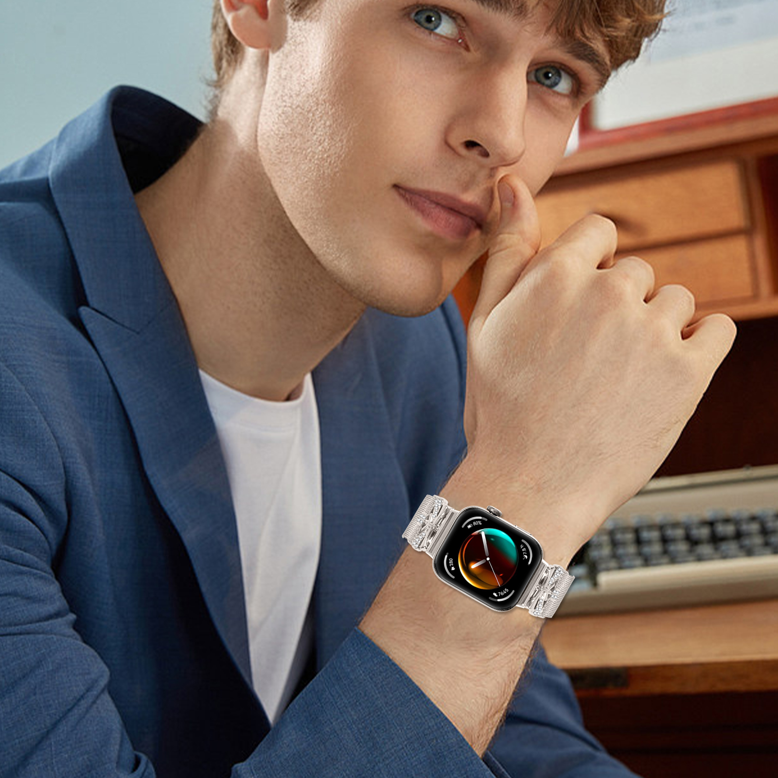 Ein Mann mit blauer Jacke und silberner Uhr mit gemustertem Armband. Er schaut auf sein Handgelenk.