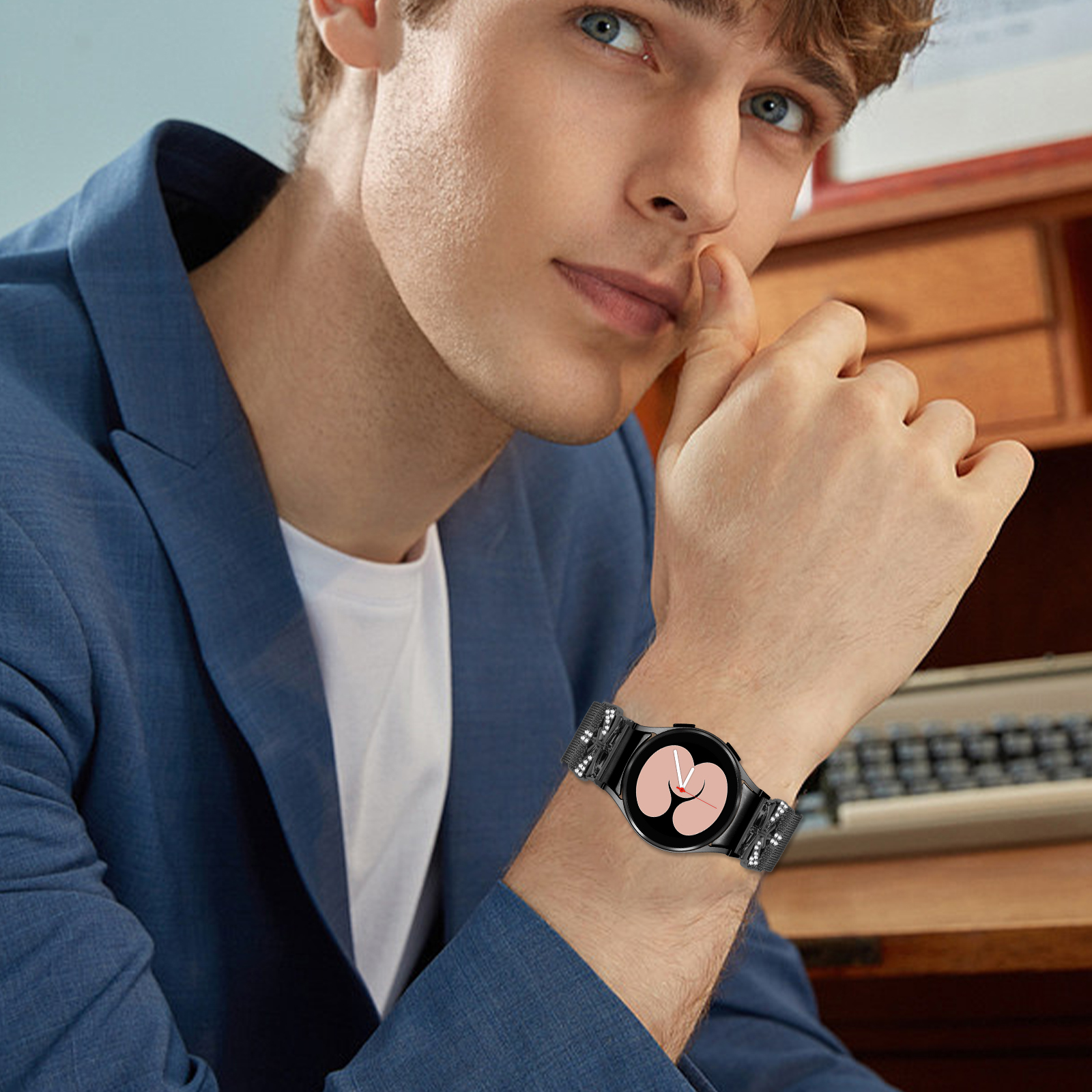 Uomo che indossa uno smartwatch nero con cinturino argentato, seduto a una scrivania.