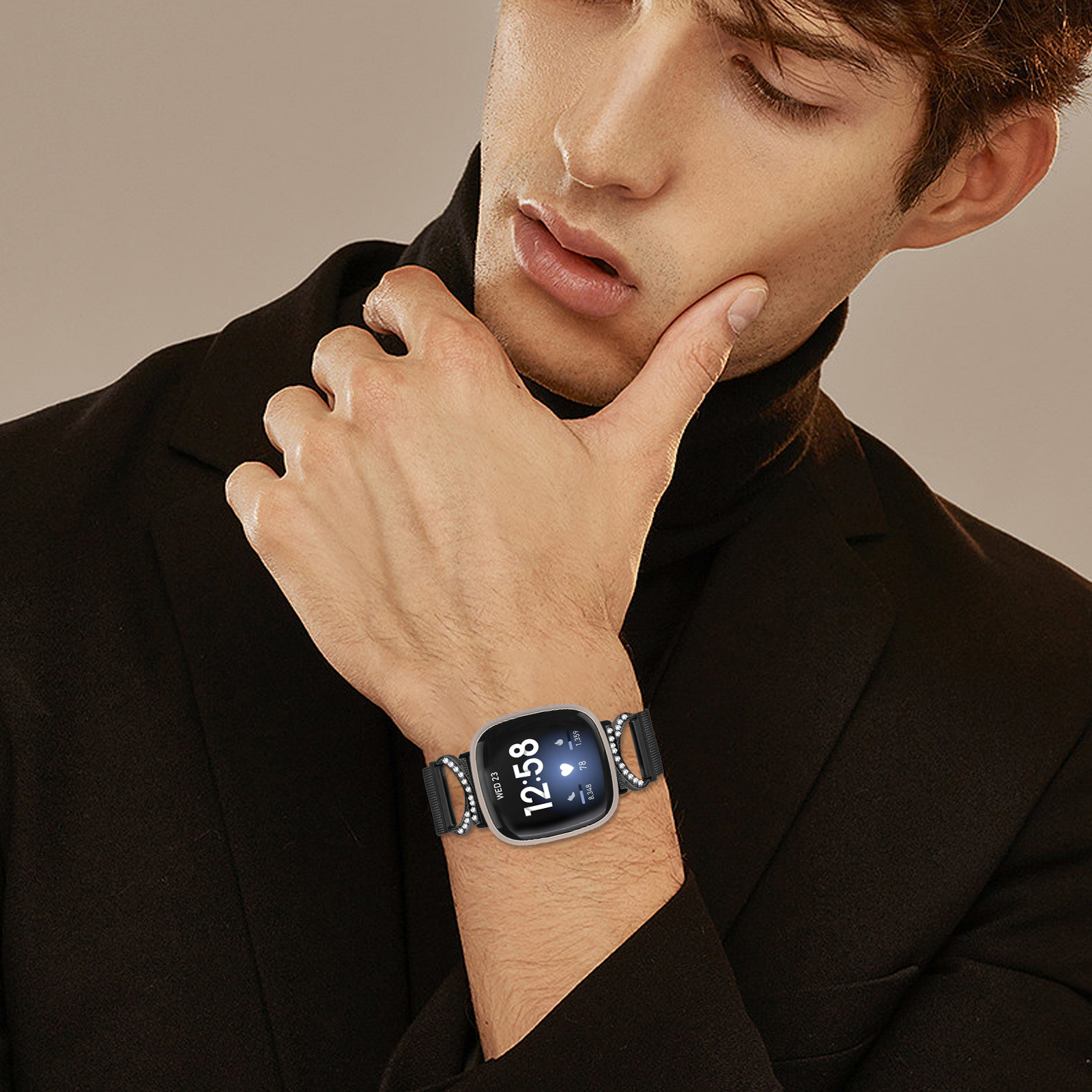 Un uomo con un dolcevita nero e un orologio con cassa argentata. L'orologio mostra l'ora.