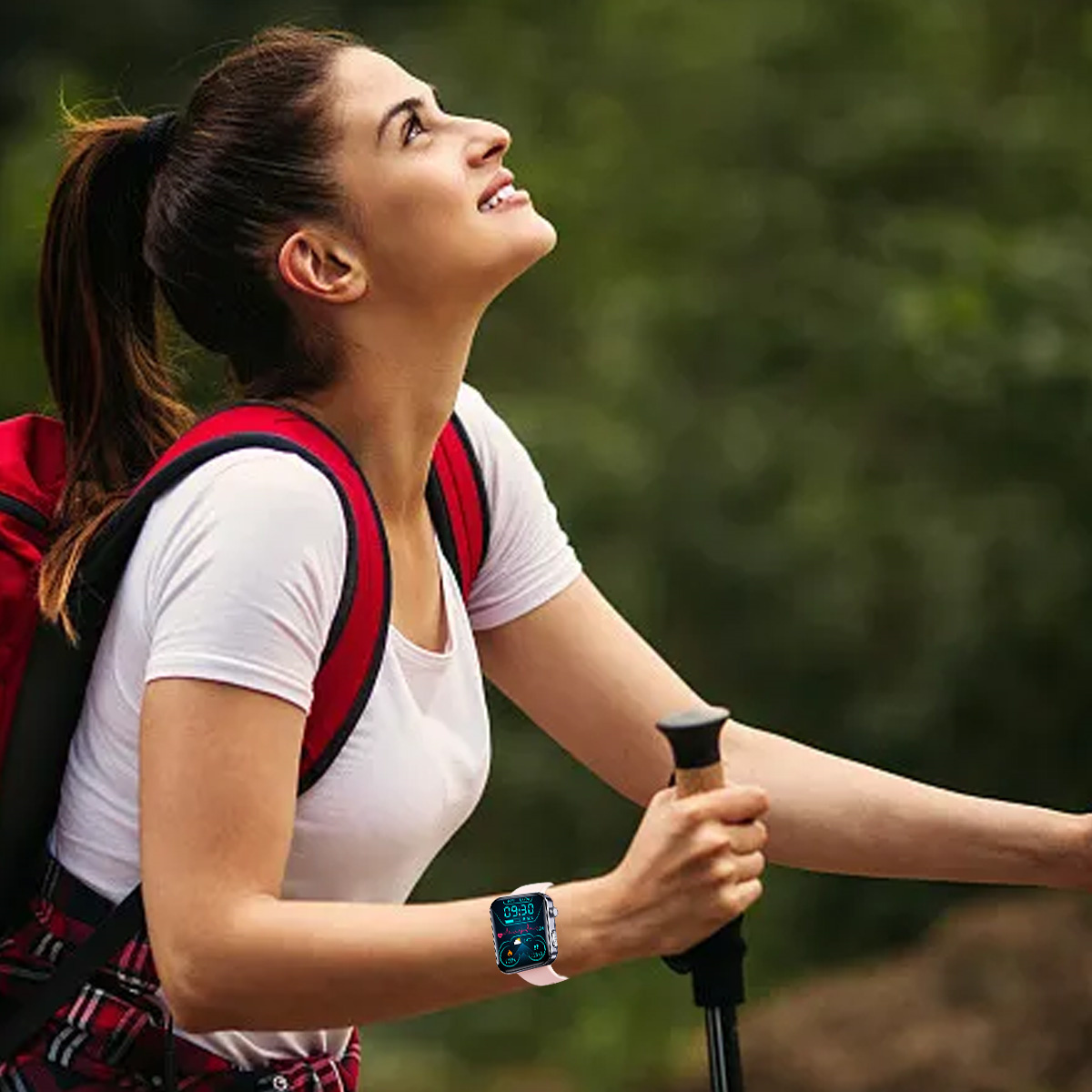 Eine Frau wandert mit Rucksack und schaut nach oben. Sie trägt eine Smartwatch.