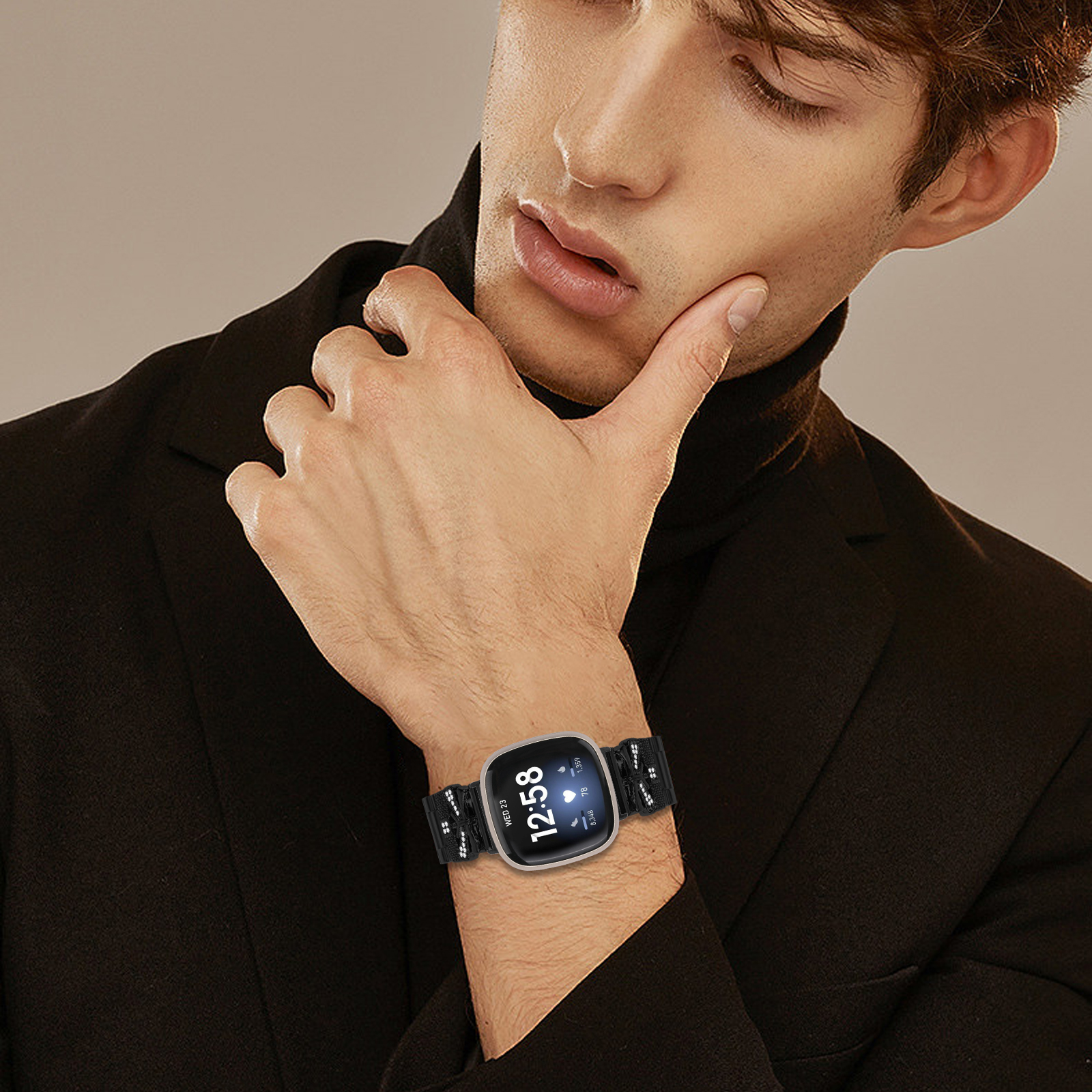 Uomo con dolcevita nero, che mostra uno smartwatch al polso.