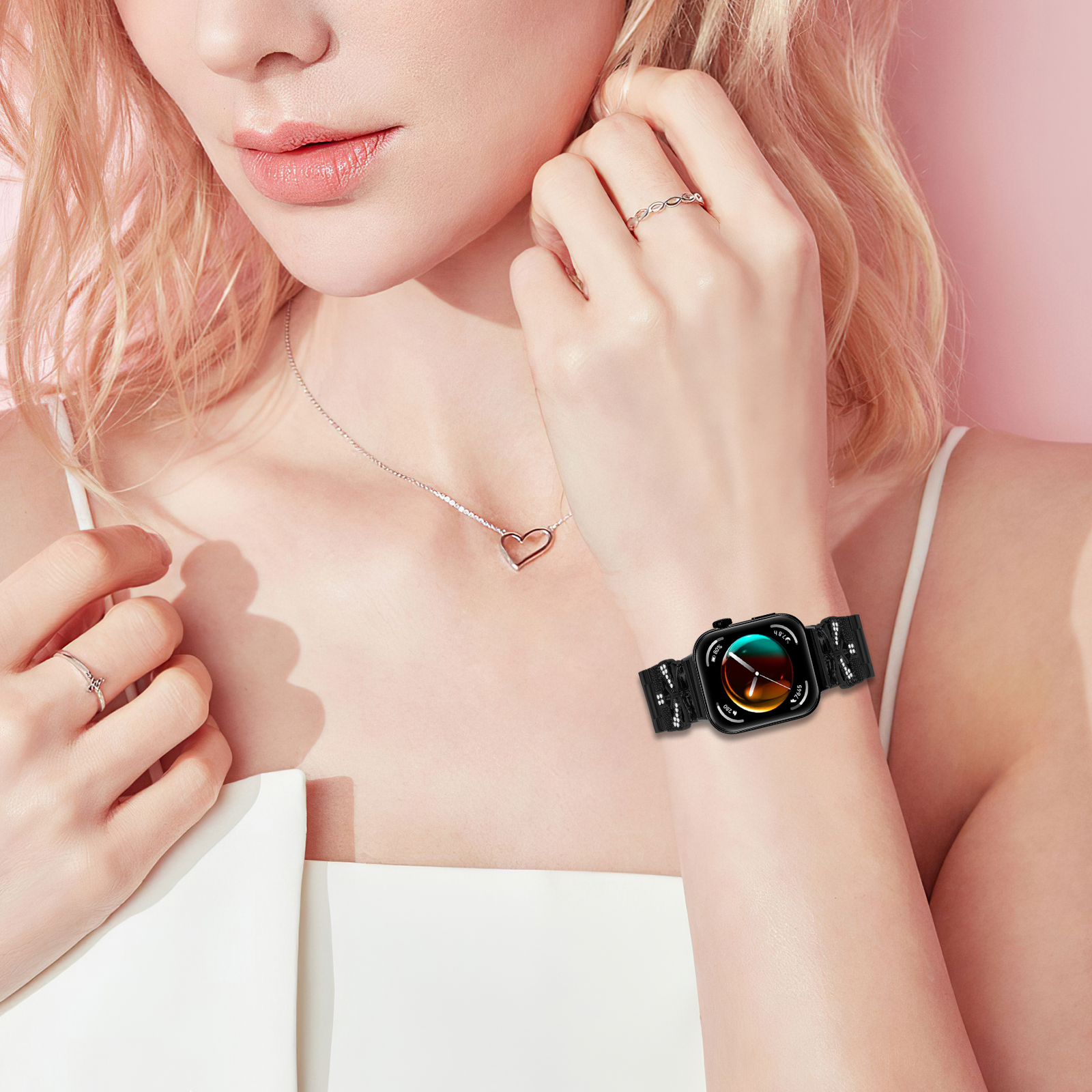 Polso di donna con smartwatch nero con schermo colorato, anelli e collana.