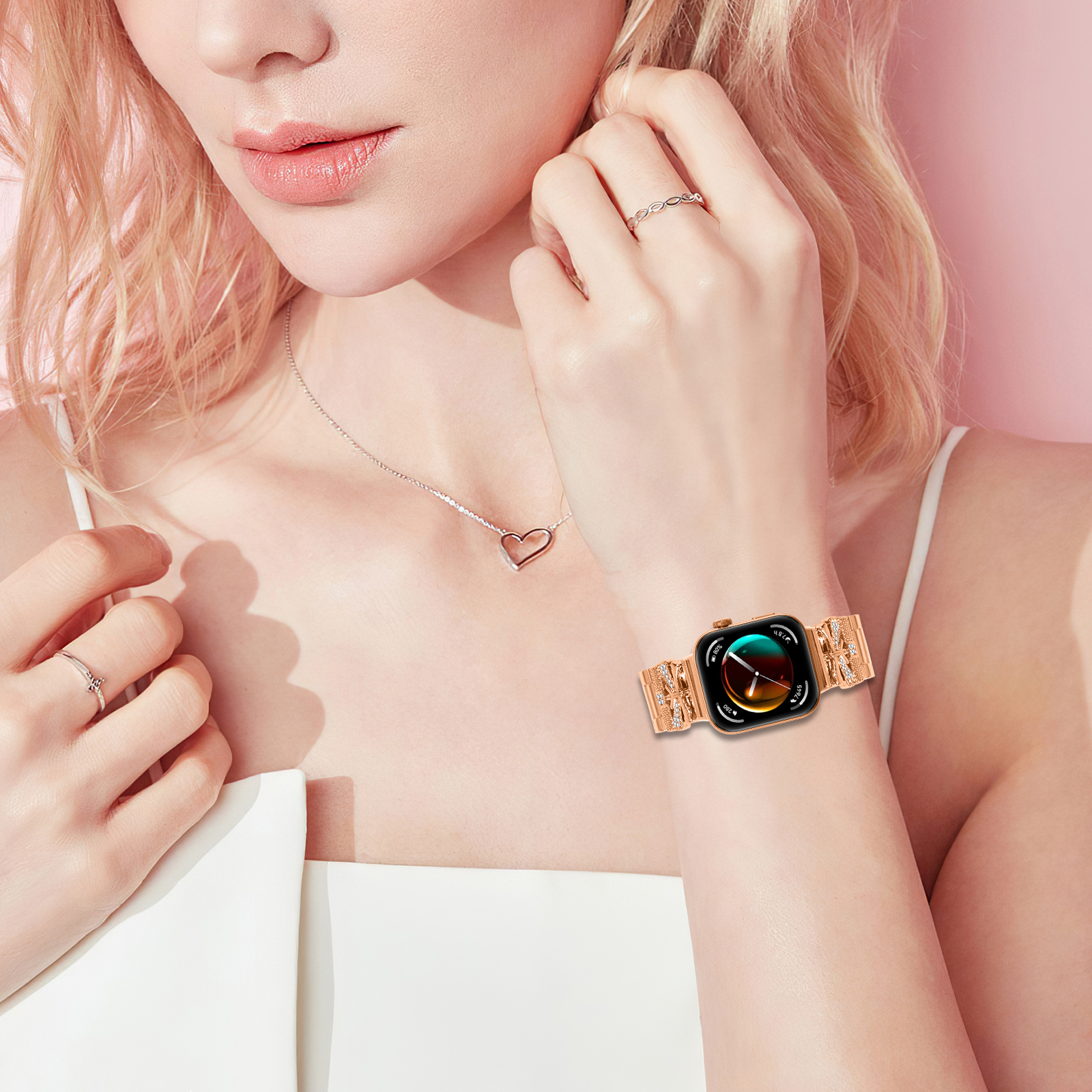 Donna con orologio oro rosa con cinturino decorativo. Sfondo rosa.