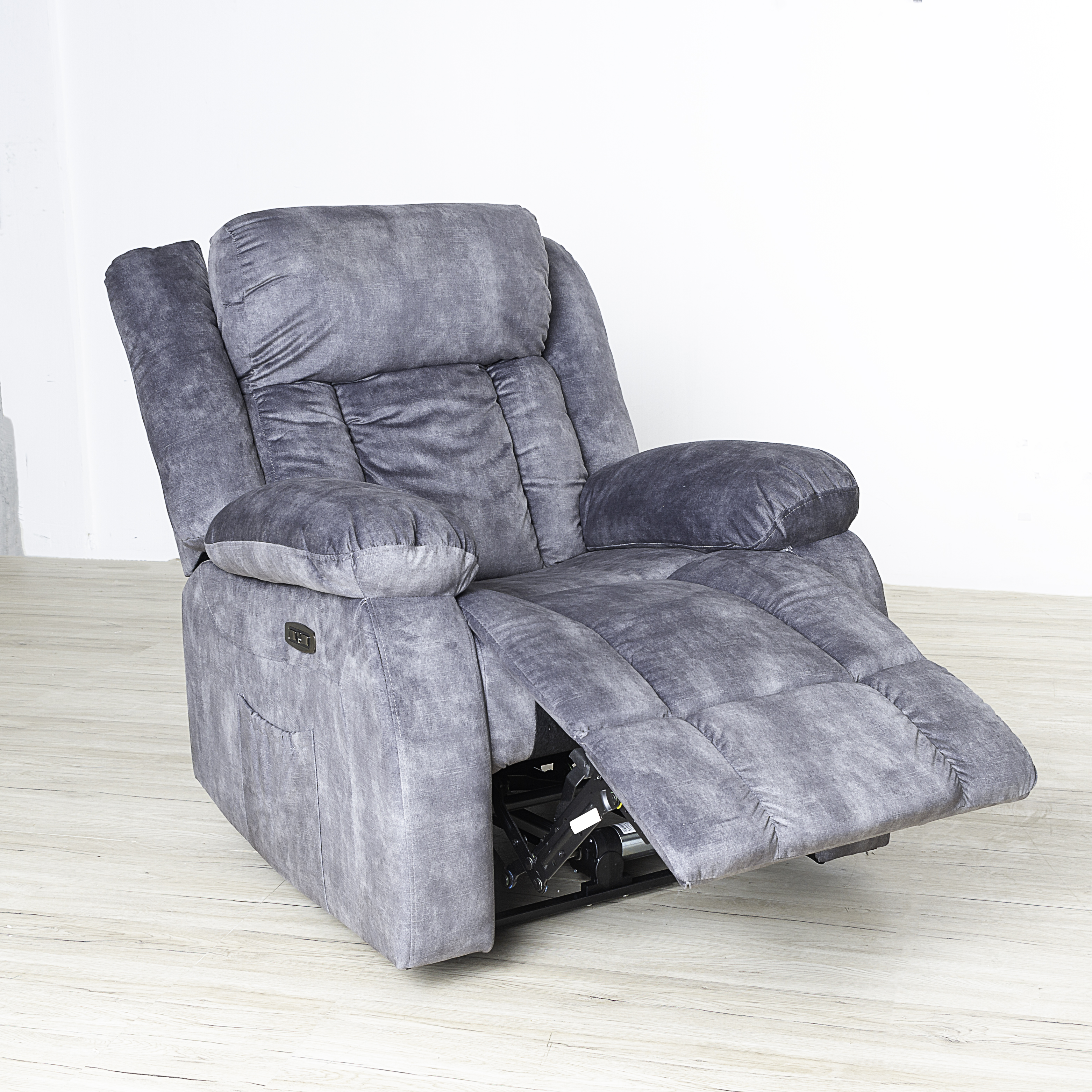 Sillón reclinable gris con reposapiés extendido en una habitación luminosa.