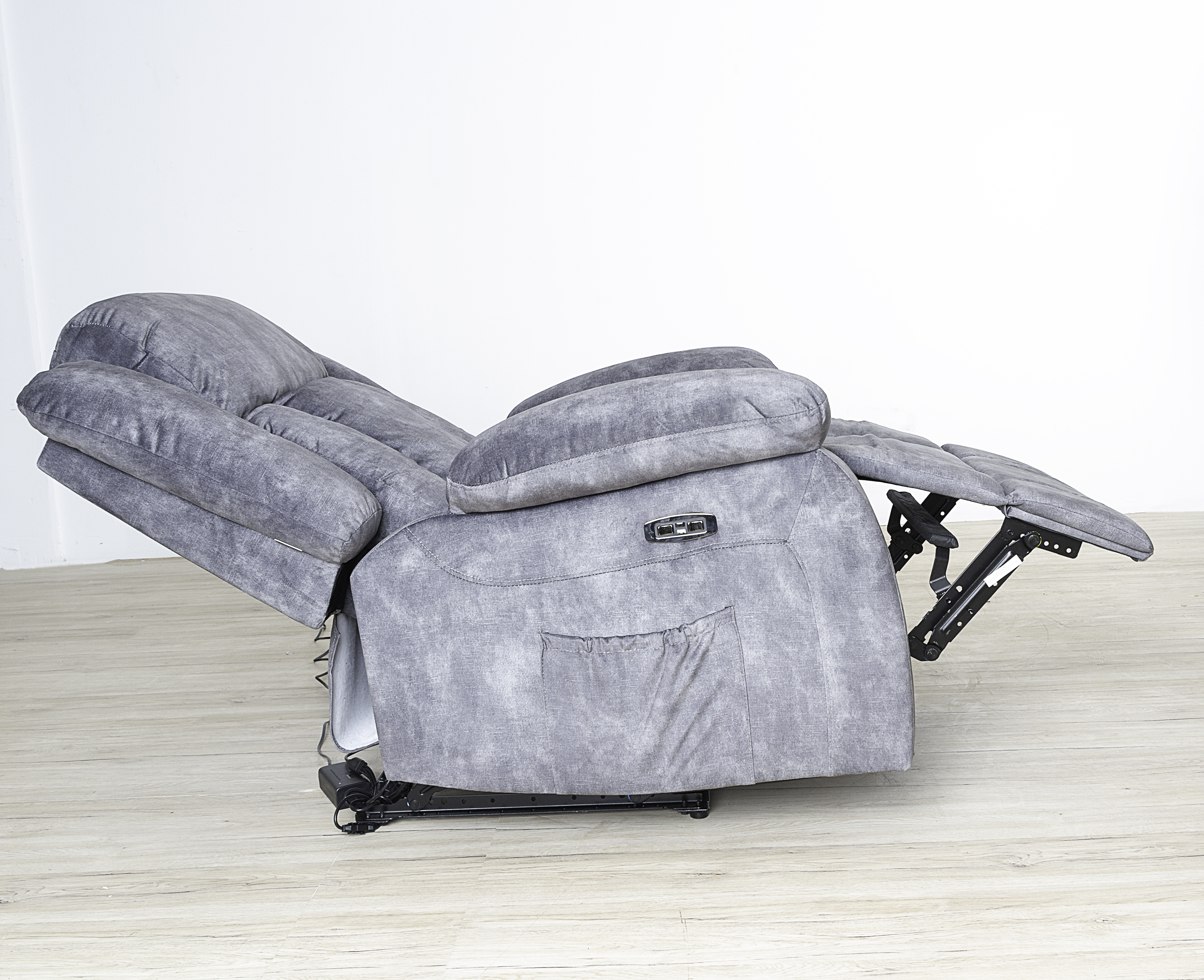 Una silla reclinable gris con el respaldo reclinado, sobre un piso de madera clara.