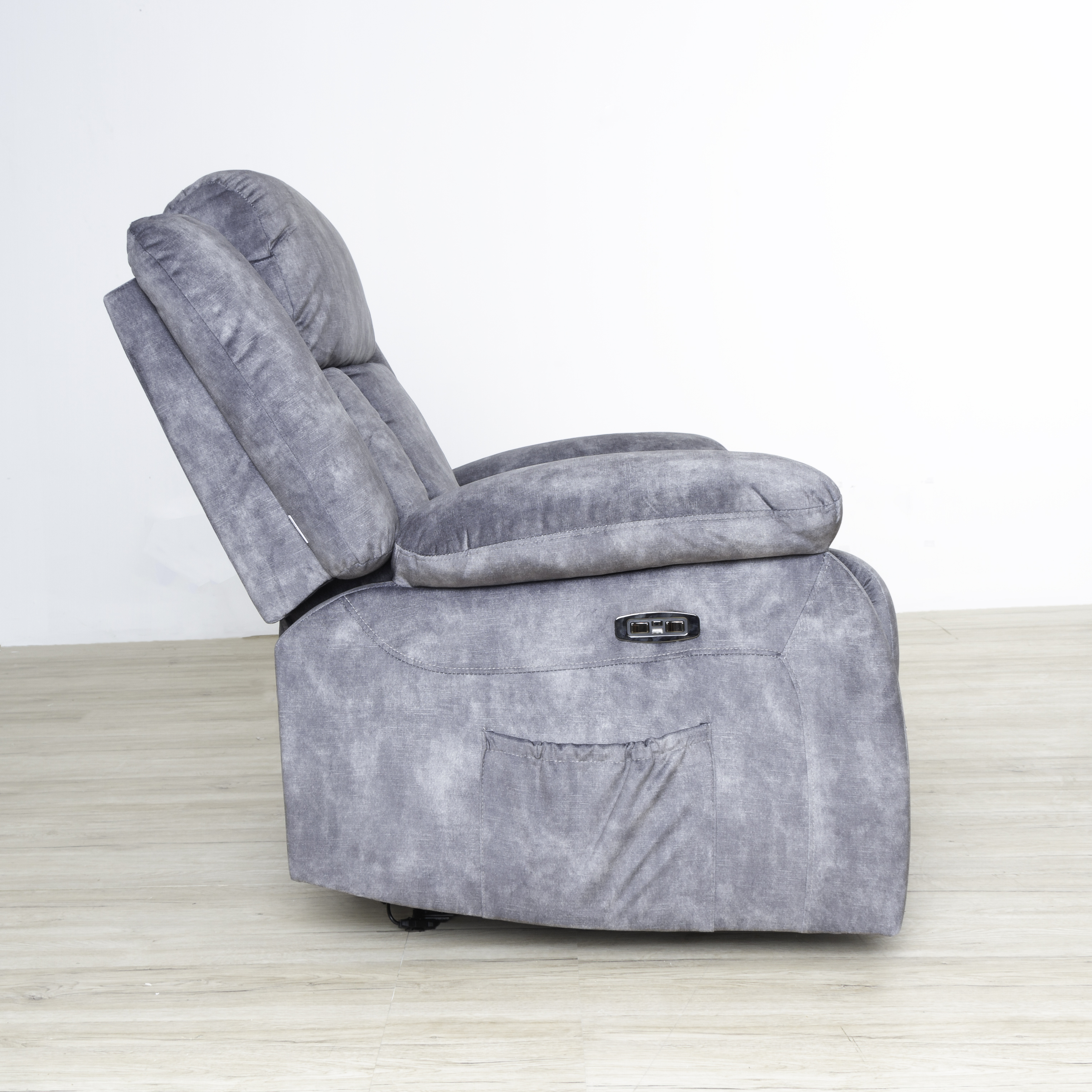 Sillón reclinable gris, vista lateral, parcialmente reclinado, con bolsillo lateral.