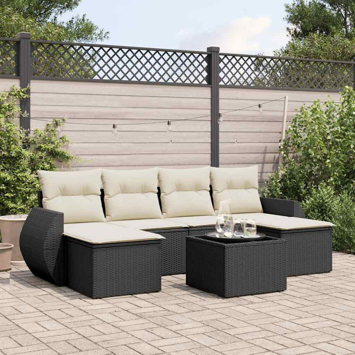 Schwarzes Korbmöbel-Set mit Kissen, Couchtisch und Ziegelterrasse.