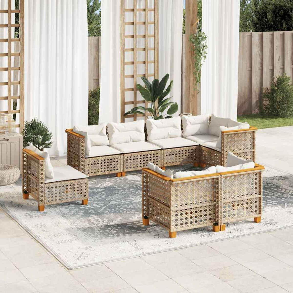 Un set patio esterno con mobili intrecciati, cuscini bianchi e un tappeto. Giorno soleggiato.
