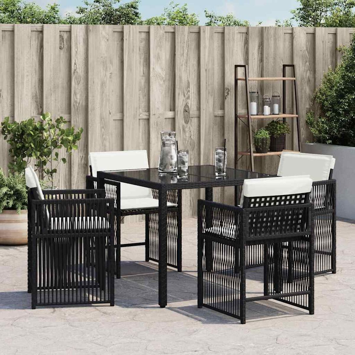 Set da pranzo per esterni. Tavolo quadrato nero e quattro sedie. Design intrecciato. Sfondo di recinzione in legno.