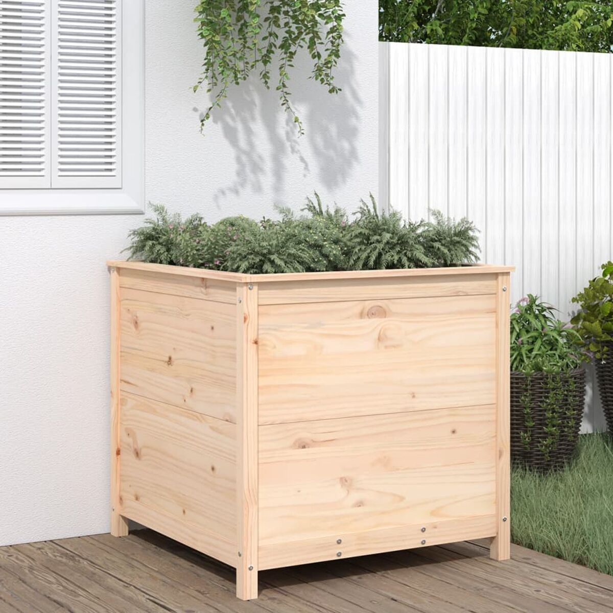Eine helle Holzpflanzkasten gefüllt mit grünen Pflanzen, platziert auf einem Holzdeck.