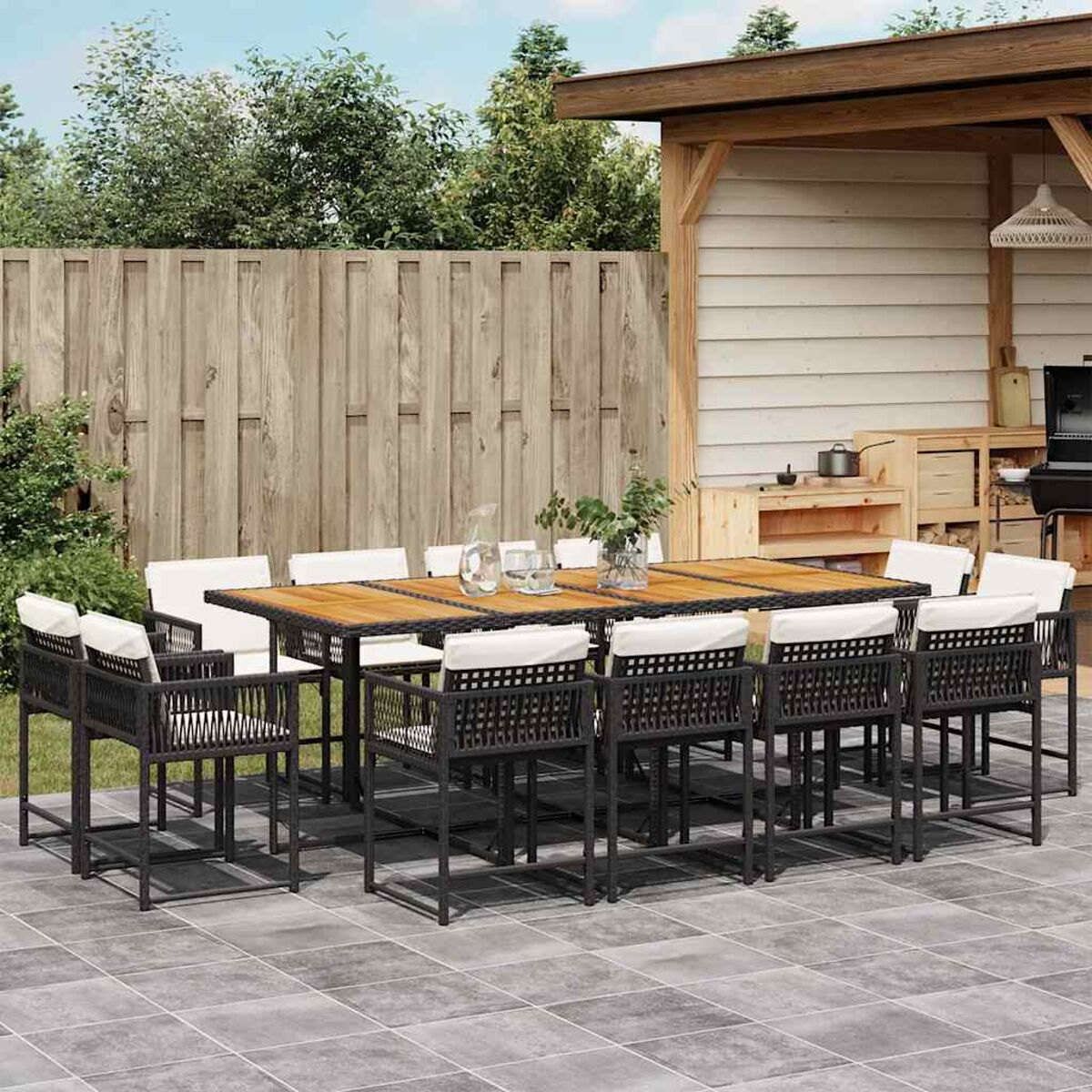 Essgruppe im Freien. Ein großer Holztisch mit Sitzgelegenheiten für zwölf Personen. Garten im Hintergrund.