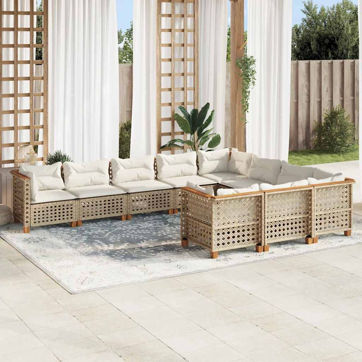 Divano angolare da esterno con cuscini color crema su un patio, tende bianche e un albero sullo sfondo.