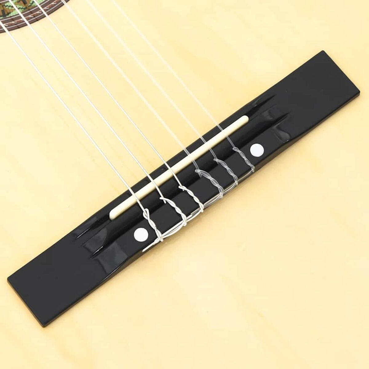 Nahaufnahme einer Gitarrenbrücke mit darüber gespannten Saiten, Holzmaserung.