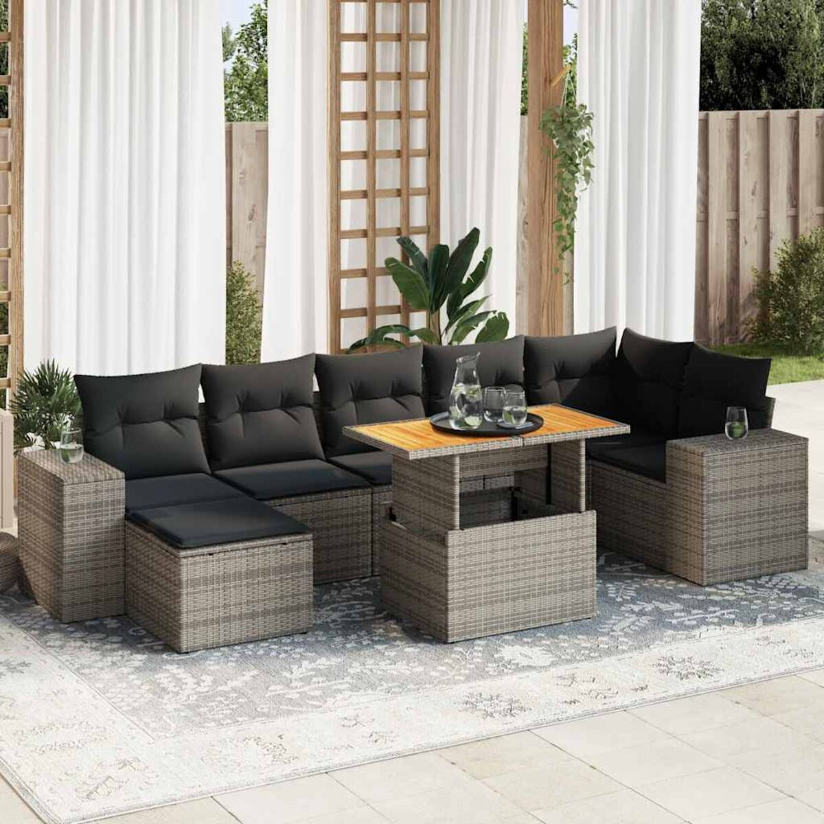 Set divano esterno in rattan con cuscini grigi e tavolo sollevabile. Tappeto chiaro.