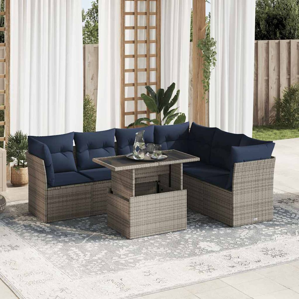 Set di mobili da esterno in vimini con cuscini blu scuro, un tavolo e un tappeto.