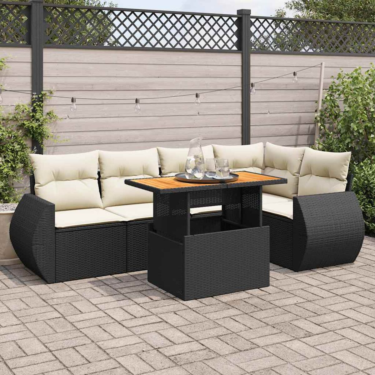 Set di mobili da esterno in vimini nero con tavolo e cuscini color crema.