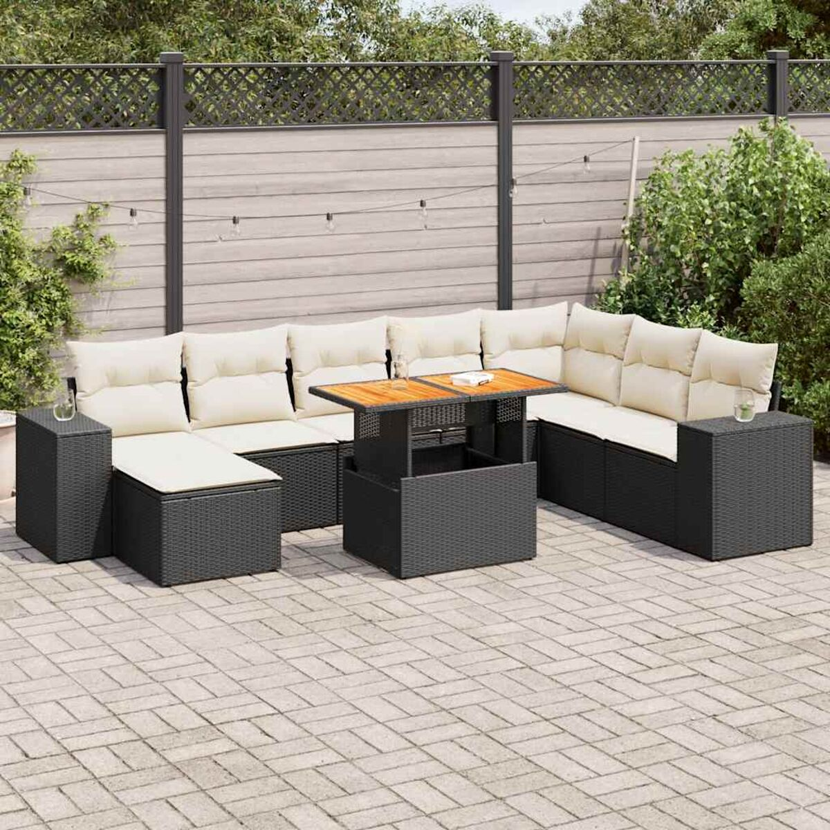 Set divani in vimini nero con tavolo e cuscini su un patio pavimentato.