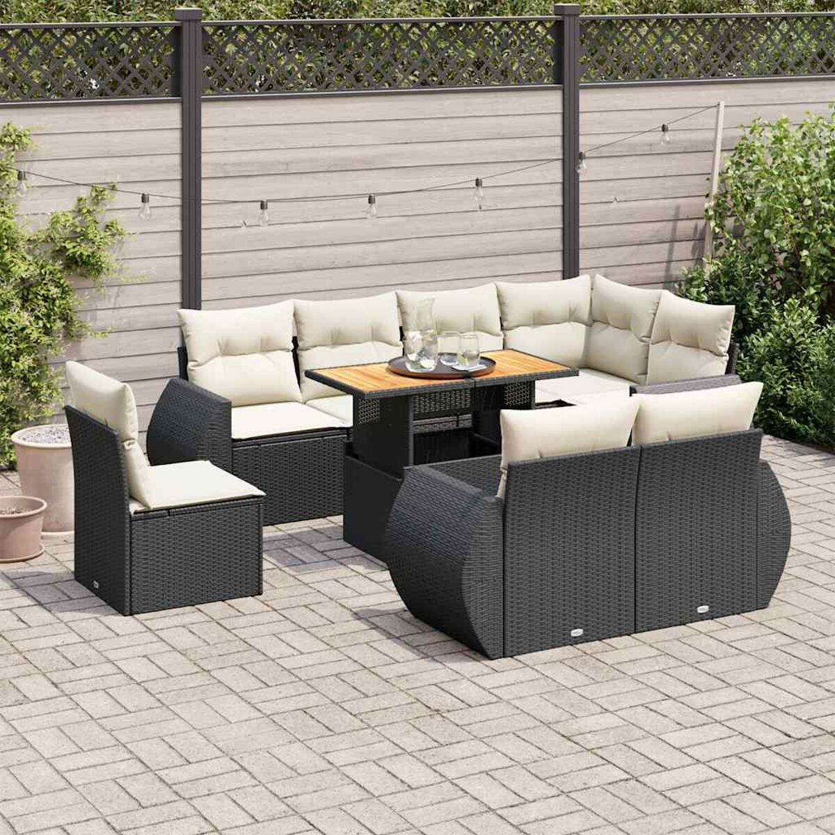 Un set da patio esterno con un design nero intrecciato, tra cui un divano, sedie e un tavolo. Sono visibili cuscini beige.