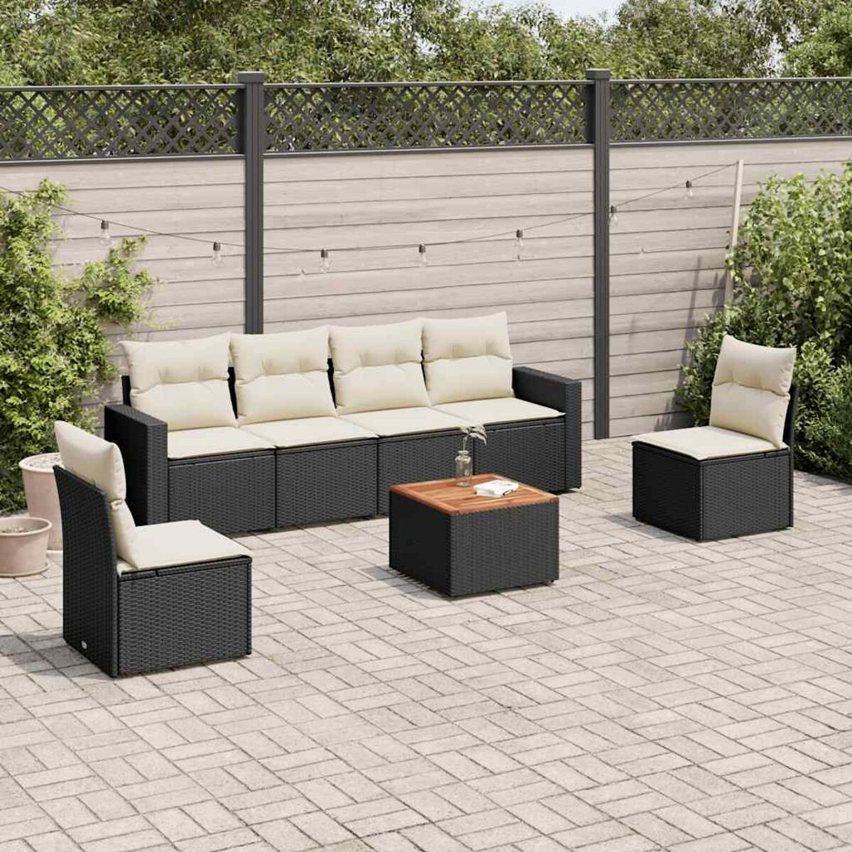 Gartenmöbelanordnung mit Sofa, zwei Stühlen und Tisch auf einer Terrasse.