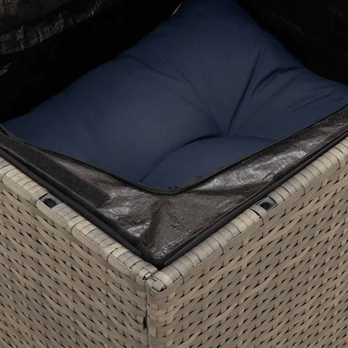 Primo piano dell'interno di un contenitore in vimini grigio con un cuscino blu navy.