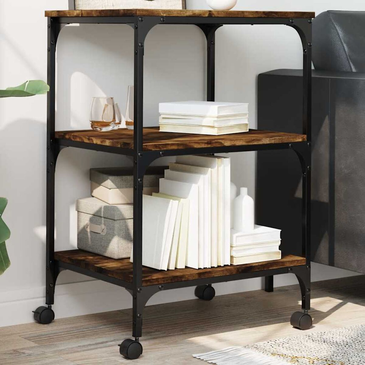 Dreistöckiges Regal auf Rädern. Aus Holz und schwarzem Metallrahmen. Bücher und Dekorationsartikel auf Regalen.