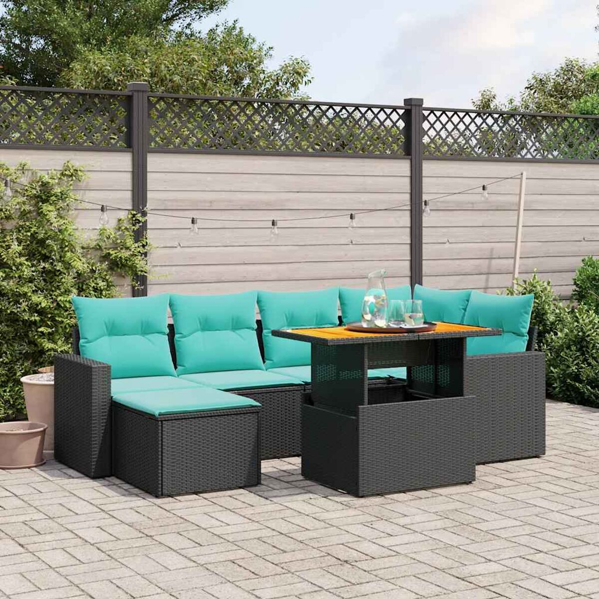 Zona de estar al aire libre con muebles de mimbre negro, cojines turquesa y mesa de madera.