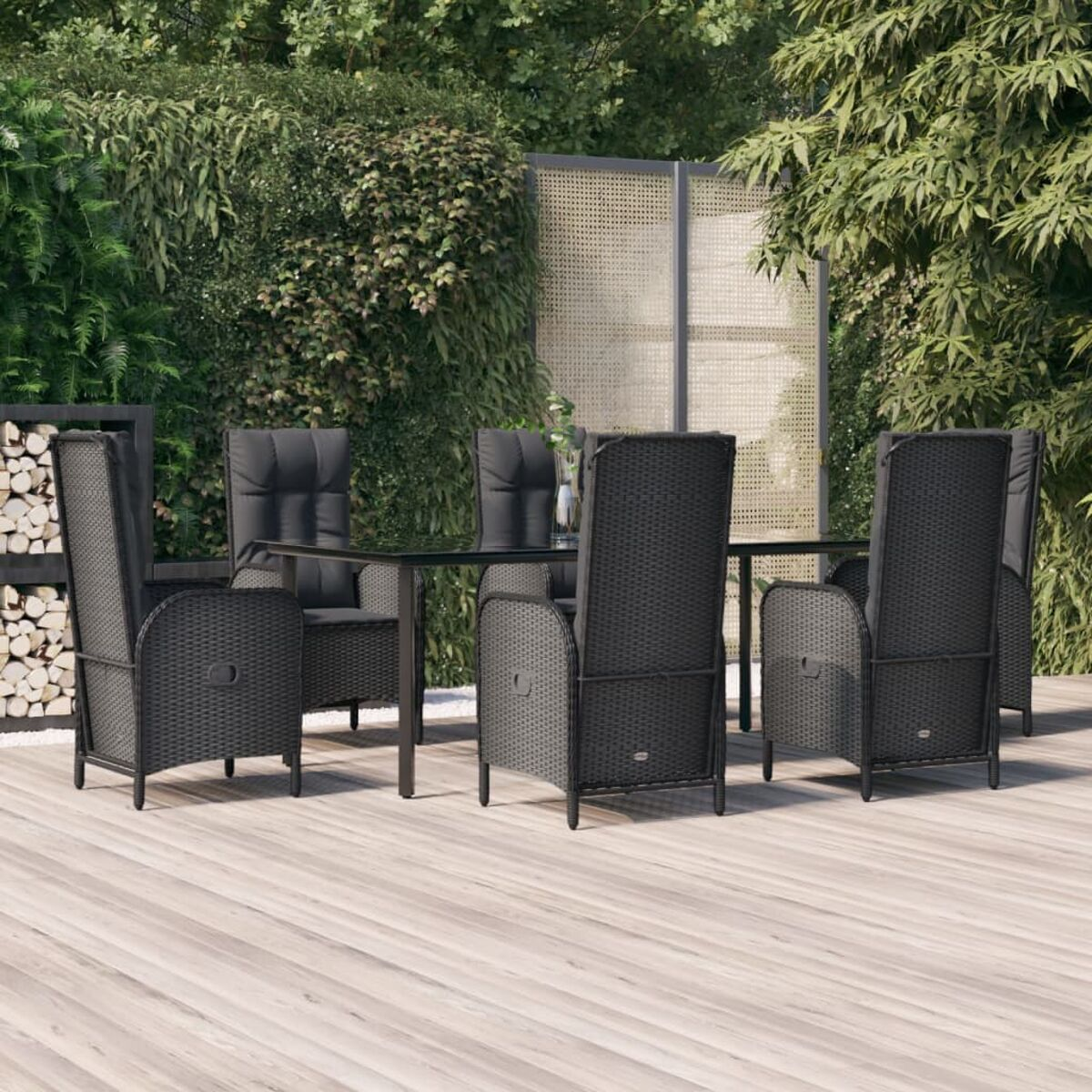 Essgruppe im Freien auf Holzterrasse. Schwarze Stühle mit Kissen und ein Glastisch.