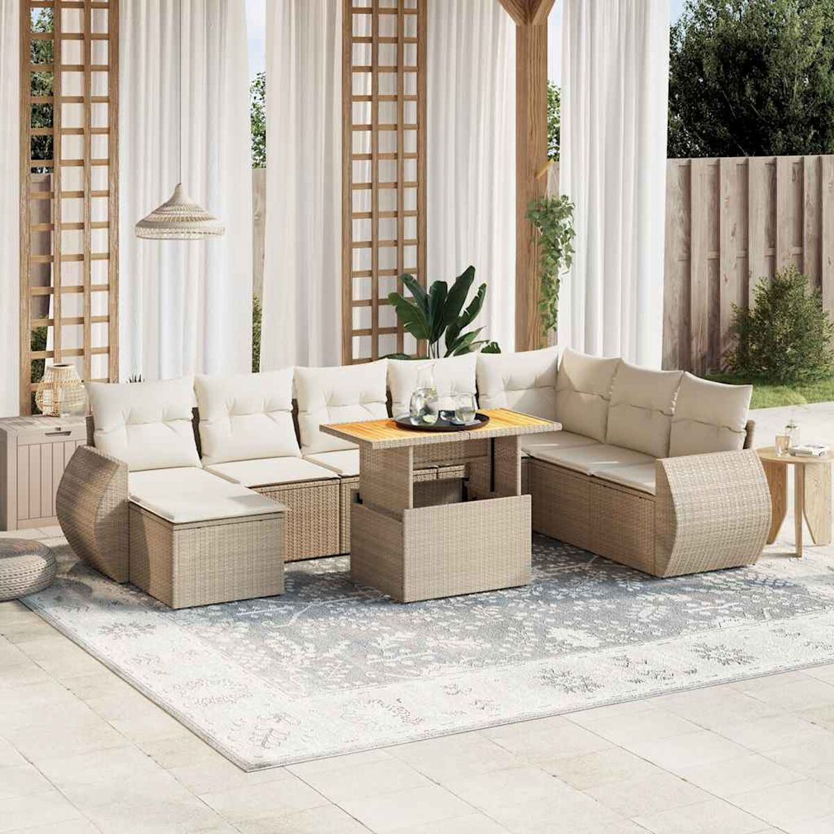 Set living esterno con tavolo sollevabile e divani componibili. Cuscini beige, tappeto e tende bianche.
