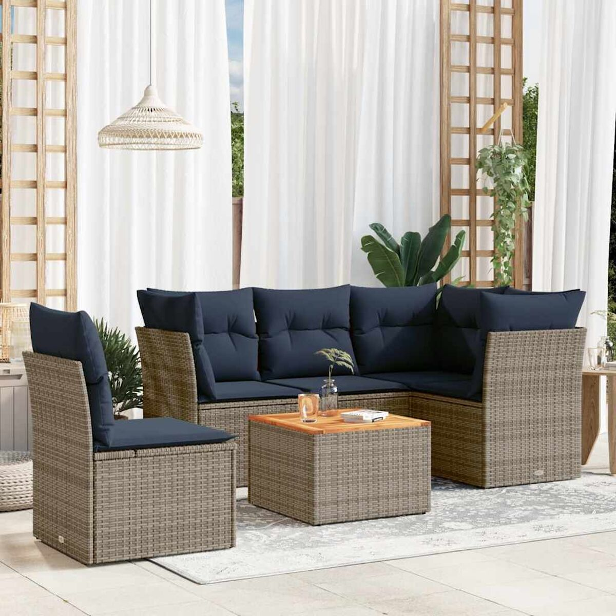 Divano angolare in rattan da esterno con cuscini blu navy e tavolino. L'ambientazione è un patio.