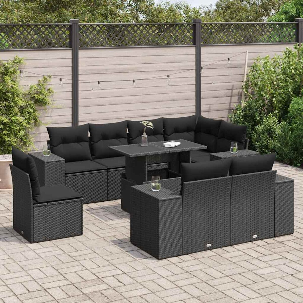 Set di mobili da esterno in vimini nero con cuscini, tavolo e un patio in mattoni.