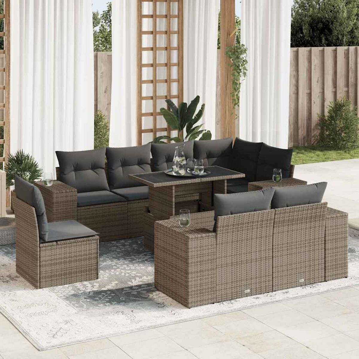 Rattan-Sofagarnitur mit grauen Kissen, auf einem gemusterten Teppich, mit einem Tisch in der Mitte.