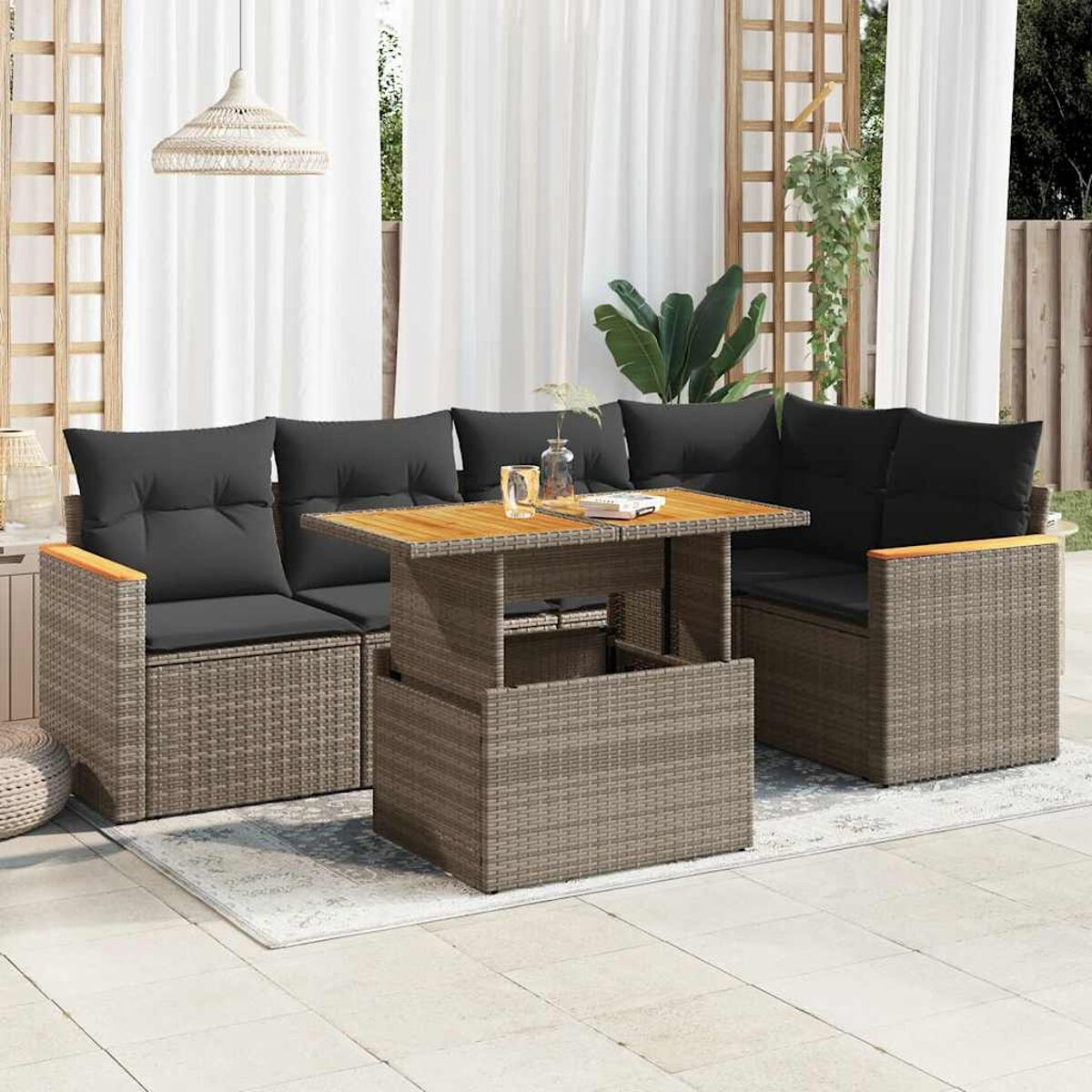 Divano angolare in rattan da esterno con cuscini neri e tavolo elevabile. Ambiente patio.