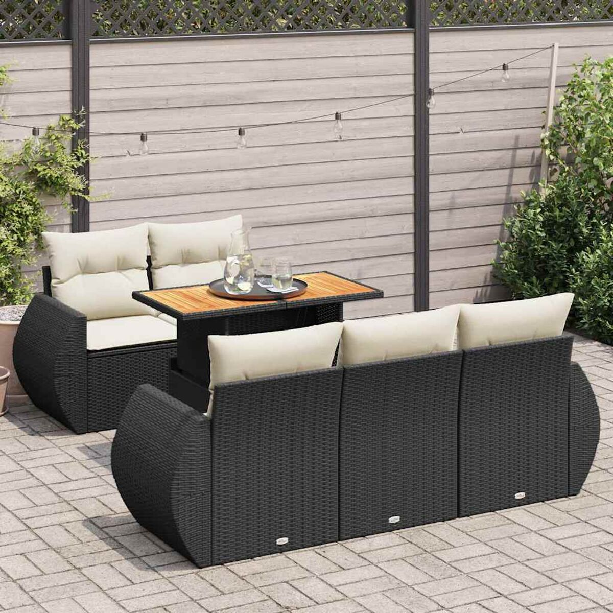 Set da patio. Vimini nero, cuscini beige, tavolo in legno. Scena cortile.