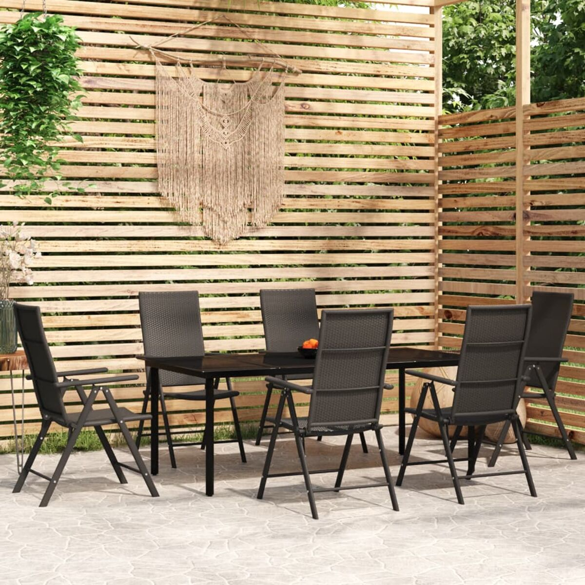 Holzlattenzaun und sechs Stühle um einen Tisch im Garten.