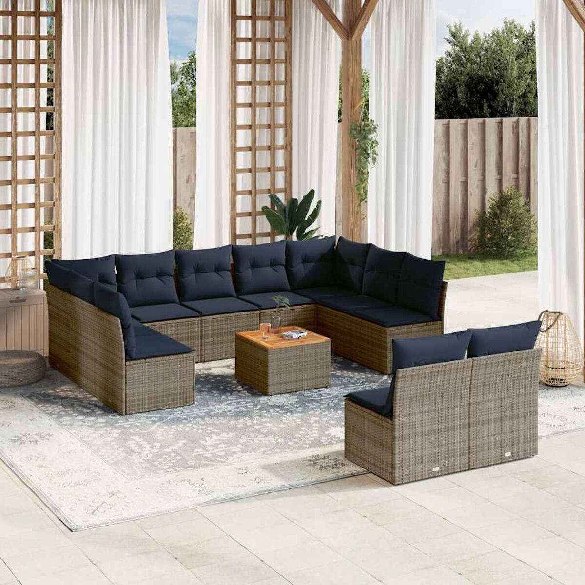 Un'area salotto all'aperto con un divano e sgabelli in rattan, cuscini blu scuro e un tavolo in legno.