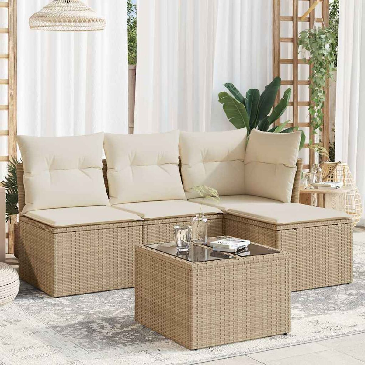 Un salotto in rattan da esterno con cuscini color crema e un tavolino con piano in vetro su un patio chiaro.