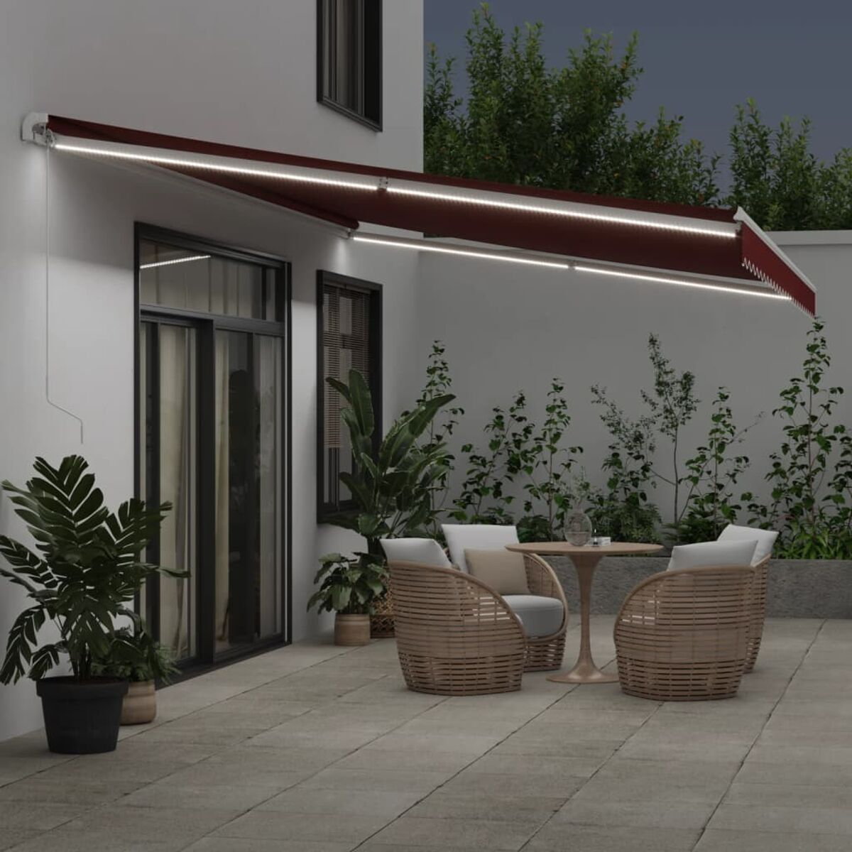 Patio esterno con tenda bordeaux, piante e area salotto con tavolo.