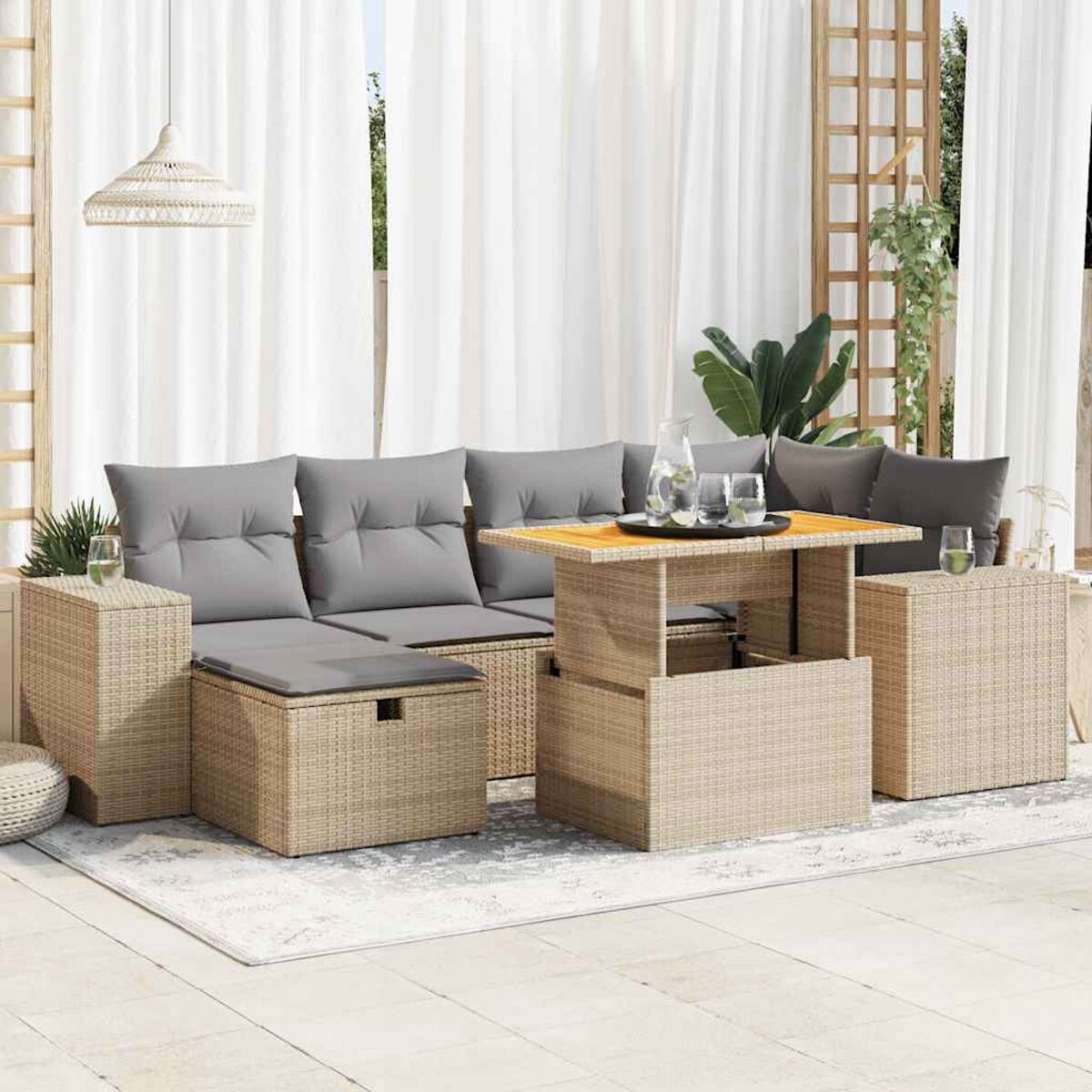 Set di mobili da esterno in vimini con divano, tavolino e due pouf, su un tappeto.
