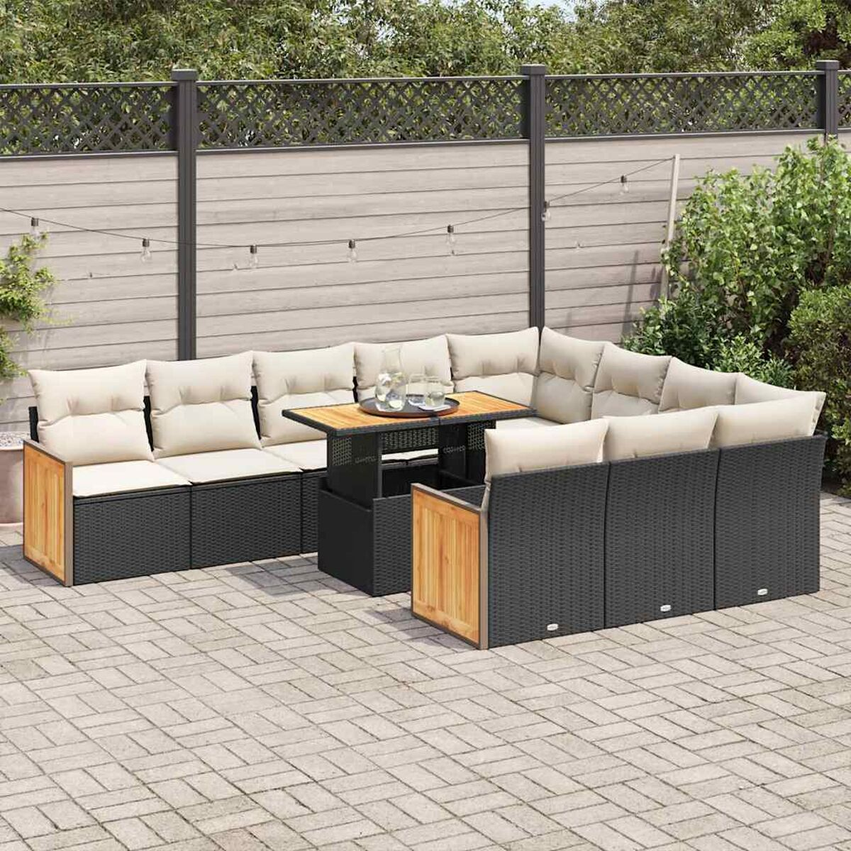 Set di divani in vimini per esterni con tavolo. I cuscini sono beige. Lo sfondo include una recinzione.