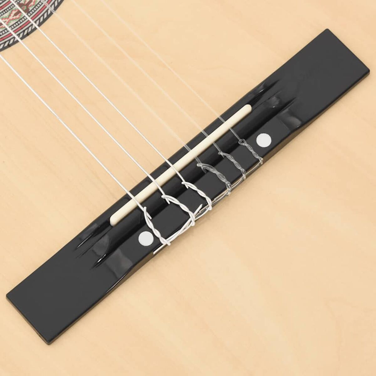 Nahaufnahme einer Gitarrenbrücke mit Saiten auf einem hölzernen Gitarrenkorpus. Schwarz und weiß.