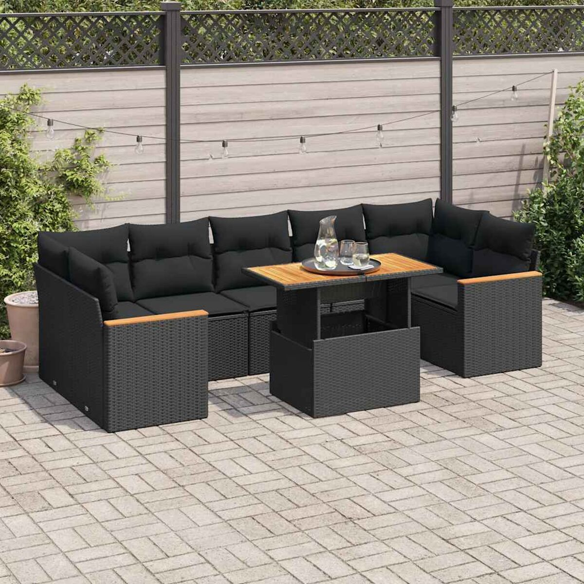 Terrassenarrangement im Freien, schwarze Korbmöbel, Couchtisch und Ecksofa im Garten.