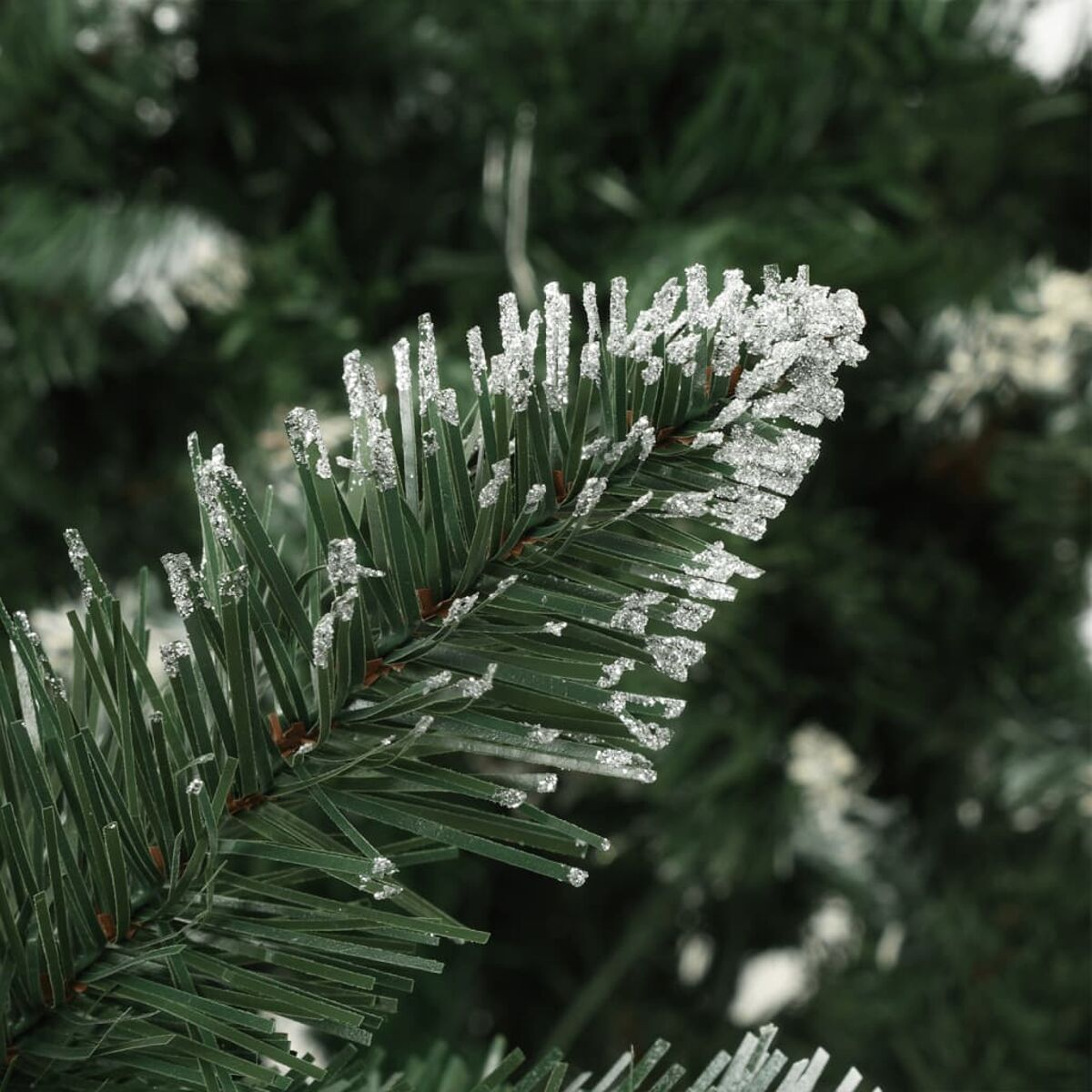 Nahaufnahme eines grünen Kiefernzweigs mit eisigen, glitzernden Kristallen auf den Nadeln.
