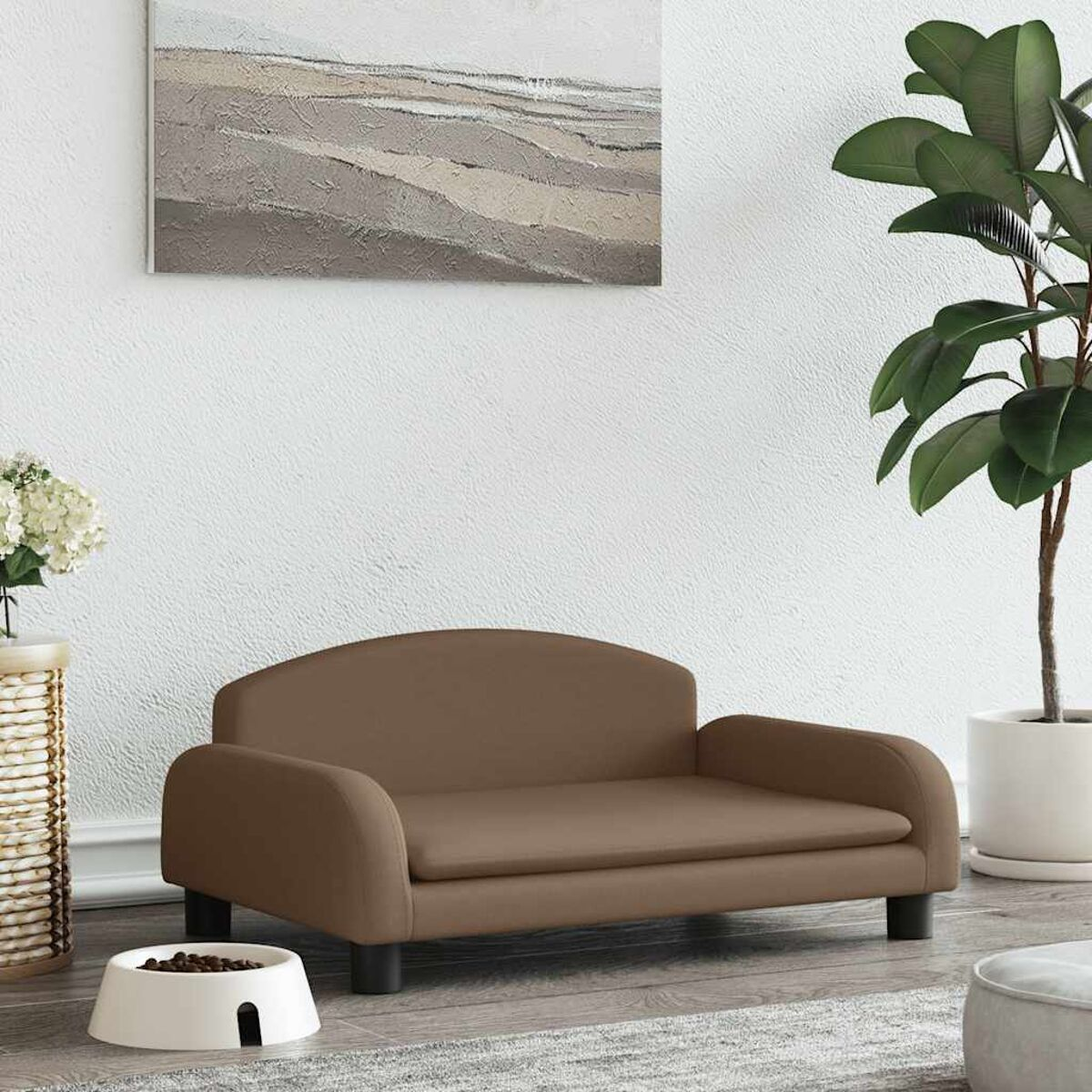 Braunes Haustiersofa mit weißer Schüssel, Gemälde und Pflanze in einem Raum.