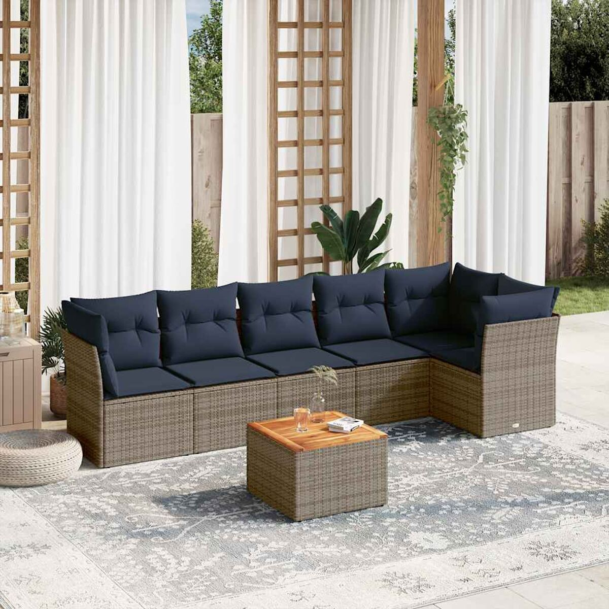Korbsessel-Ecksofa mit marineblauen Kissen. Tisch und Teppich im Bild.