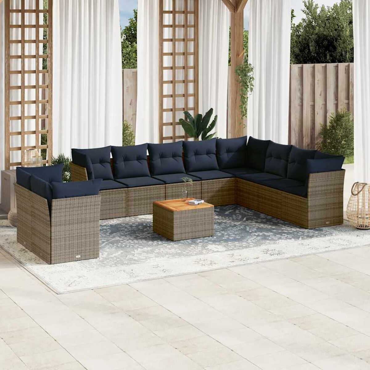 Set patio esterno con mobili in vimini marrone, cuscini blu e tavolo in legno.
