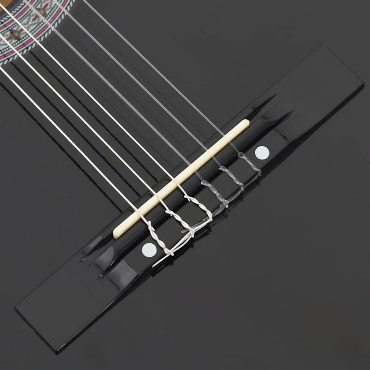 Nahaufnahme des Stegs und der Saiten einer schwarzen Gitarre.
