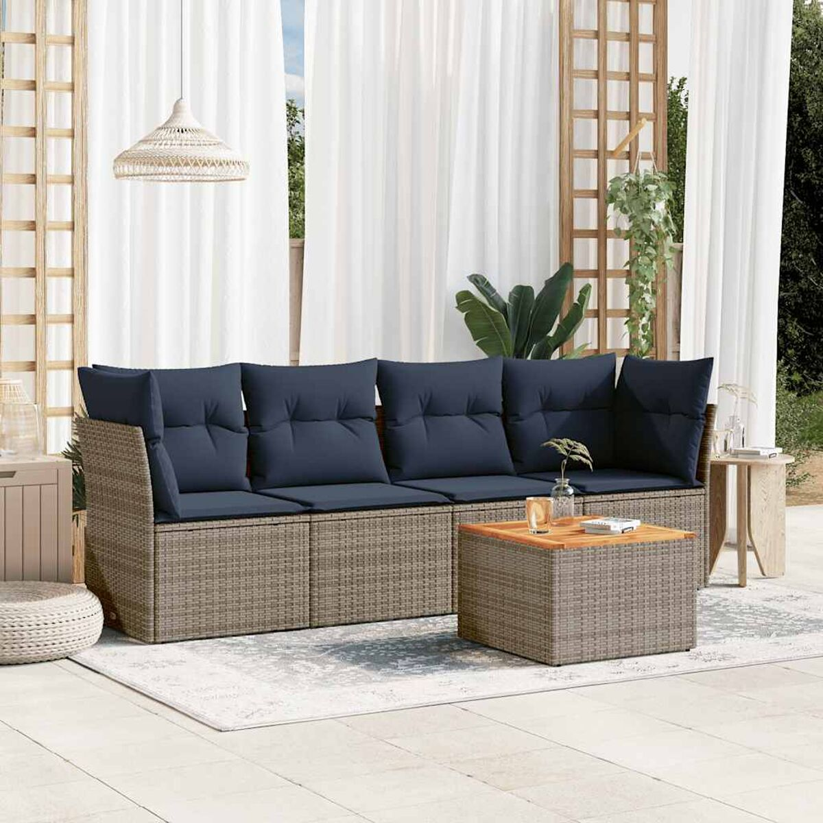 Set divani in vimini con cuscini blu, tavolo e accessori su un patio.