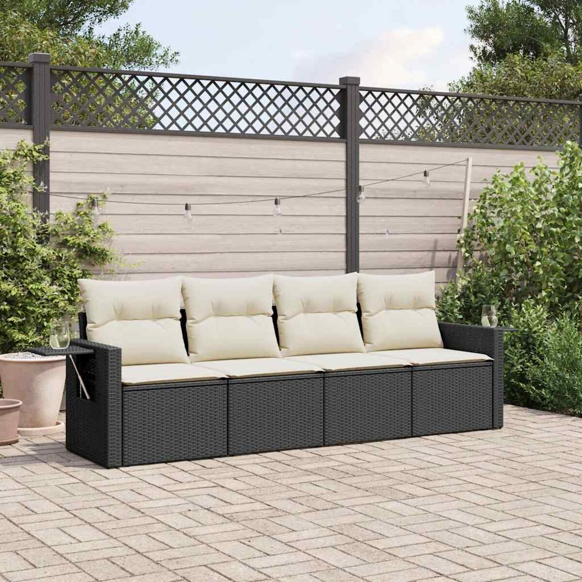 Ein dunkelgraues Rattan-Sofa mit cremefarbenen Kissen auf einer Ziegelterrasse.