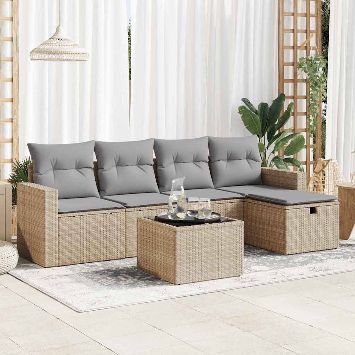 Ein beiges Rattansofa mit grauen Kissen und einem Couchtisch im Freien.